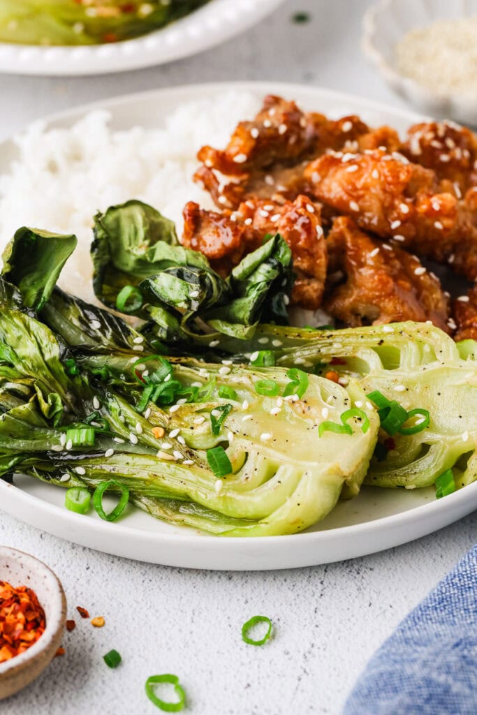 A highlight from my Food Photography Portfolio: a plate with white rice, crispy glazed chicken, and sautéed bok choy garnished with sesame seeds and chopped green onions.